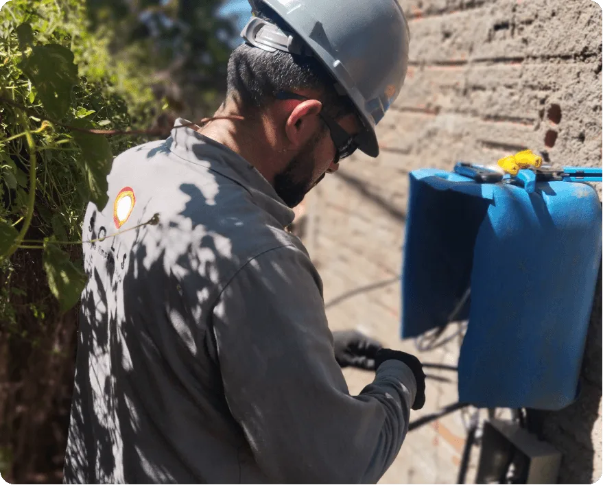 Técnico da Solls com capacete e óculos de proteção trabalhando em quadro elétrico