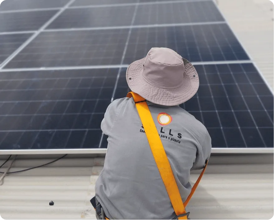 Técnico da Solls com cinto de segurança fixando módulos solares em telhado