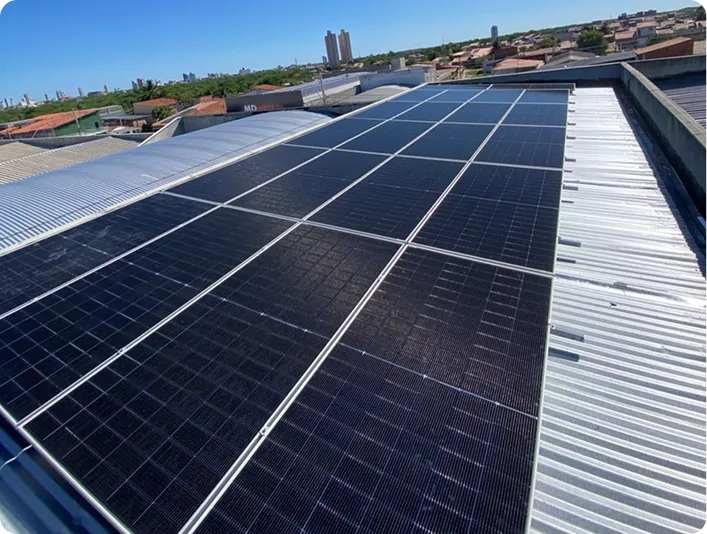 Painéis solares instalados em telhado metálico industrial com a cidade ao fundo